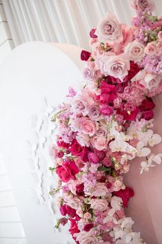 pink and white flowers are arranged on the side of a heart - shaped wall decoration