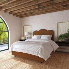 a large bed sitting in a bedroom next to an arched window and wooden flooring