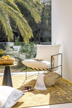 a white chair sitting on top of a rug next to a table with a bowl of fruit