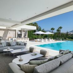 a living room with couches and tables near a swimming pool