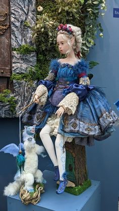 a doll sitting on top of a tree next to a stuffed animal