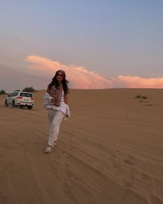 a woman is walking in the desert near a truck