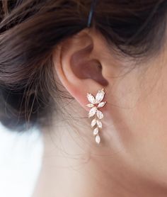 a close up of a woman's ear wearing a pair of gold and crystal earrings