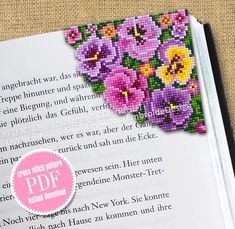 an open book with cross stitch flowers on it