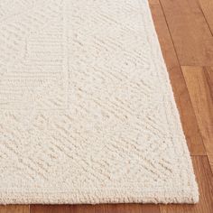 a white rug on the floor with wood floors in the background and a wooden floor