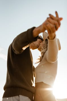 a man and woman standing next to each other holding their hands up in the air