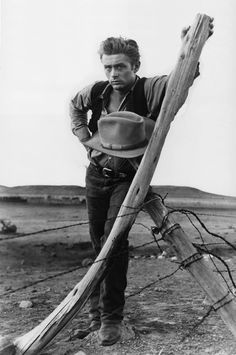 a man leaning on a wooden pole in the desert