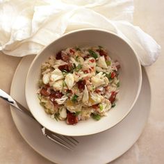 a white bowl filled with food on top of a table next to a fork and napkin