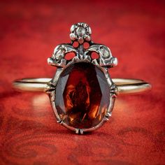 An exquisite Georgian inspired ring boasting a deep red flat cut Garnet weighing approx. 2.5ct framed in a closed back Silver gallery with 18ct Gold band. A Fleur de Lis can also be seen growing out from the top and is dotted with three twinkling rose cut Diamonds. It's a fabulous tribute to Georgian design and looks gorgeous laid flat against the finger. We recommend you insure for £1,750. We can provide a written Valuation on completion of the sale. WEIGHT: 2.6 grams MEASURES: Size J ½ (UK), 5 Formal Garnet Gemstone Diamond Ring, Oval Red Rose Cut Diamond Jewelry, Red Oval Rings With Rose Cut Diamonds, Formal Red Diamond Ring With Rose Cut Diamonds, Victorian Style Red Oval Diamond Ring, Victorian Oval Red Diamond Ring, Classic Red Pear-shaped Rings, Classic Pear-shaped Red Rings, Antique Red Oval Diamond Ring