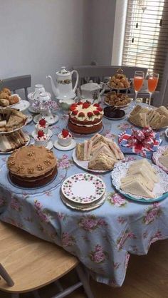 a table topped with cakes and desserts on top of a blue table cloth covered table