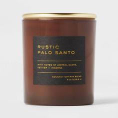 a candle that is sitting on top of a white surface with the words rustic palo sano written in gold