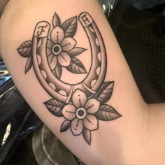 a black and white photo of a tattoo with flowers on the arm that has an anchor in it