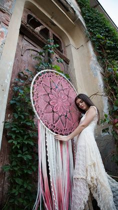 a woman in a white dress is holding a pink and white doily dream catcher