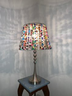 a lamp that is sitting on top of a small table in front of a wall