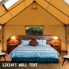 a bed sitting inside of a tent next to two tables and lamps on either side of the bed