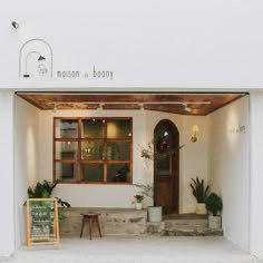 the front entrance to mission at bondy with potted plants in pots and a sign