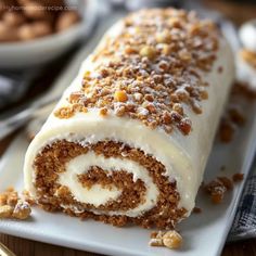 a close up of a cake roll on a plate with some nuts in the background