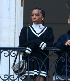 two women standing next to each other on a balcony looking at something in the distance