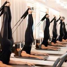 there are many women doing yoga exercises on the treadmills in this room with mirrors