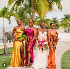 four beautiful women standing next to each other in front of palm trees and the ocean