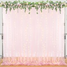 a pink backdrop with flowers and greenery on the top for a wedding or special event