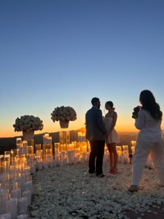 two people standing next to each other in front of candles and flowers on the ground