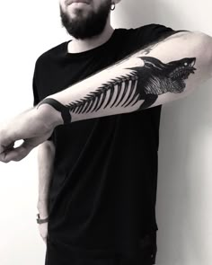 a man with a tattoo on his arm is holding onto a fish skeleton and pointing it at the viewer