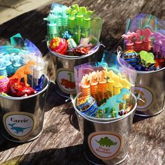 four buckets filled with different colored candies on top of a wooden table next to each other