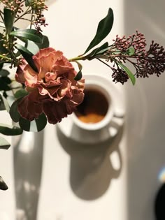 a cup of coffee and some flowers on a table