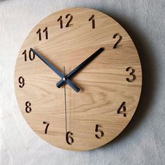 a wooden clock with black numbers on the face and hands is shown in front of a white wall