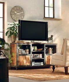 a living room with a chair, television and large clock on the wall above it