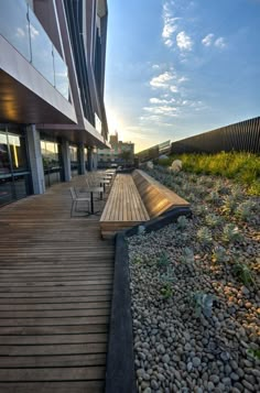 a wooden bench sitting on top of a lush green hillside next to a tall building