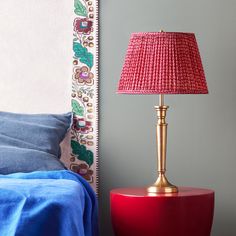 a red table lamp next to a blue bed