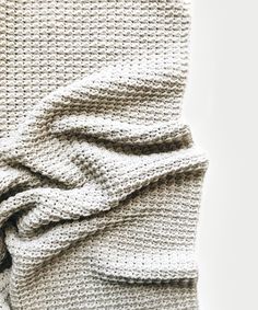 a white knitted blanket folded on top of each other with a knot at the end