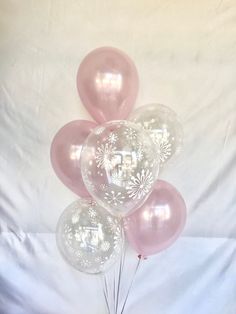 a bunch of pink balloons sitting on top of a white sheet covered ground with snowflakes