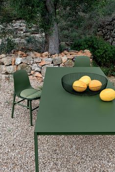 a green table with some fruit on top of it and two chairs around the table