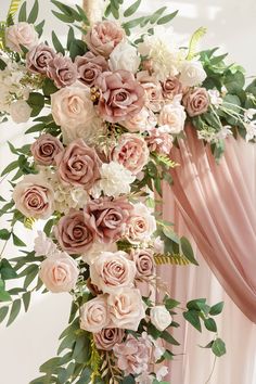 an arrangement of pink and white flowers hanging from the ceiling