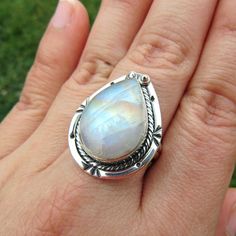 SKU: SS-061Material: 925 stamped sterling silverGemstone(s): Rainbow Moonstone (N)Gemstone Dimensions: 13 X 19 X 4 mmRing Size: US 8Weight: 8.1 gramsThis eye-catching Rainbow Moonstone ring features a teardrop Rainbow Moonstone cabochon, set in a classic bezel with a modern braid border that accents the stone beautifully. This Rainbow Moonstone lives up to its name, showcasing blue, orange and yellow fire all throughout the stone. Adjustable Teardrop Moonstone Ring In Sterling Silver, Handmade Moonstone Teardrop Ring, Silver Teardrop Cabochon Rings, Silver Pear-shaped Moonstone Jewelry, White Teardrop Moonstone Ring In Sterling Silver, Teardrop Moonstone Gemstone Ring, Teardrop Moonstone Ring For Gift, Pear-shaped Silver Gemstone Jewelry, Silver Teardrop Moonstone Ring