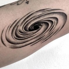 a black and white photo of a person's arm with a spiral tattoo on it