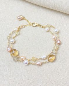 Fall in love with this layered gold bracelet, featuring a stunning combination of pale pink and golden gemstones intricately paired with luminous freshwater pearls. Meticulously handcrafted, this luxe and sophisticated piece is designed to elevate any outfit, whether you're dressing up for a special occasion or adding a touch of elegance to your everyday wear. The seamless interplay of colors and textures creates a visually captivating accessory that truly stands out. Each strand of this layered