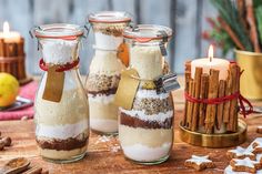 three jars filled with food sitting on top of a table next to cinnamon sticks and an apple