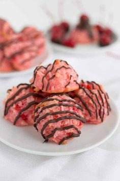 there are some cookies on the plate with chocolate drizzled on them and raspberries in the background