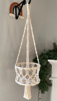 a white macrame hanging from a hook on the wall next to a potted plant