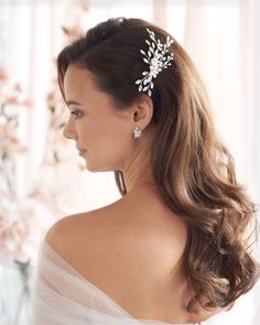 a woman wearing a wedding hair comb with flowers on it's head and shoulder