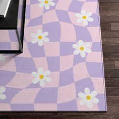 a purple and white rug with daisies on the floor next to a black table