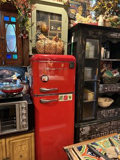 a red refrigerator freezer sitting next to a wooden cabinet