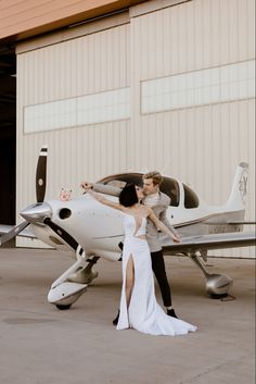 a bride and groom standing in front of an airplane