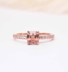 an engagement ring with a pink sapphire and diamonds on it's sidestrap