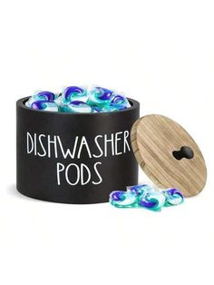 the dishwasher pods are filled with blue and white swirly glass pebbles in a black container