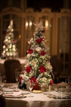 a christmas tree decorated with red and white flowers on a table in a fancy restaurant